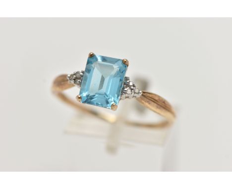 A 9CT GOLD TOPAZ AND DIAMOND RING, designed with a rectangular cut light blue topaz, in a four claw setting, flanked with sin