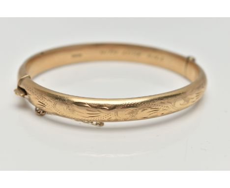 A 9CT GOLD HINGED BANGLE, floral pattern to the front, fitted with an integrated push piece clasp with additional safety chai