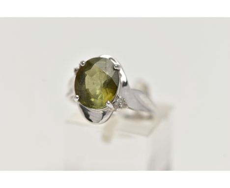 A 9CT WHITE GOLD, TOURMALINE AND DIAMOND RING, designed with an oval cut green tourmaline in a four claw setting, flanked wit