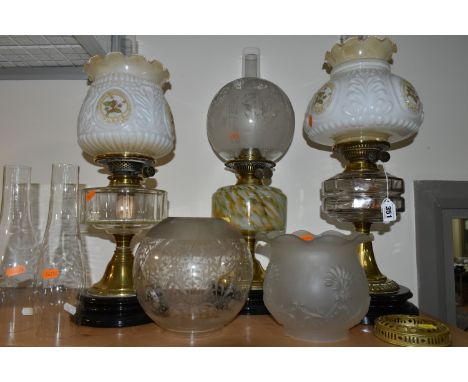 THREE OIL LAMPS AND A SELECTION OF SHADES, the oil lamps all having glass reservoirs - one with green, orange and white glass