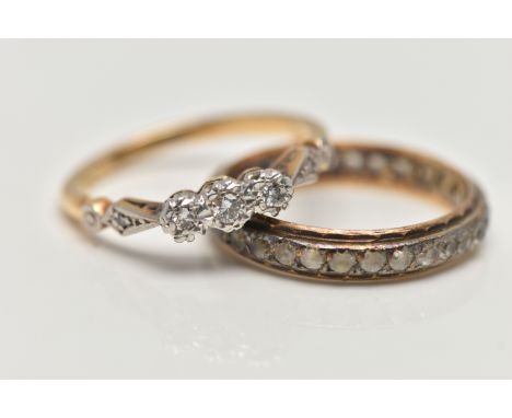 TWO YELLOW METAL RINGS, the first a three stone diamond ring, set with a central round brilliant cut diamond flanked with sin