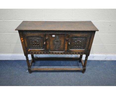 A TITCHMARSH AND GOODWIN STYLE OAK SIDE CABINET, with a carved frieze under the panel having carved detail, flanked either si