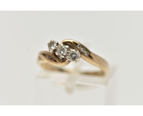 A 9CT GOLD THREE STONE DIAMOND RING, designed with three small round brilliant cut diamonds, each claw set, crossover shoulde