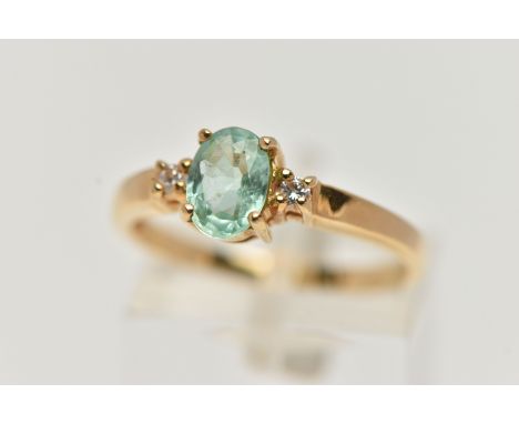 A GEM SET RING, designed as a central oval light green stone assessed as tourmaline, flanked by brilliant cut diamonds, to th