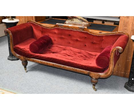 A Victorian Carved Scroll End Sofa, with buttoned velvet upholstery and on reeded support with brass castors, 210cm by 67cm b