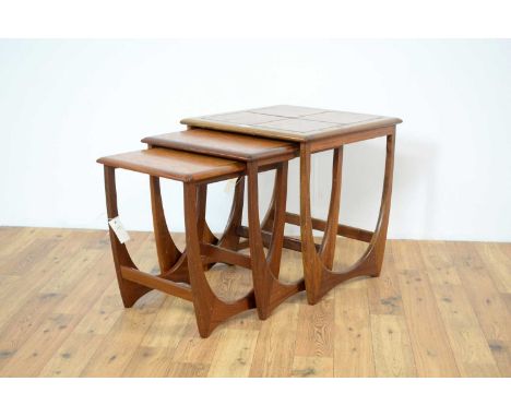 Attributed to Gplan: A teak nest of graduated tables, the segmented faux ceramic table top with chamfered edge, raised on sha