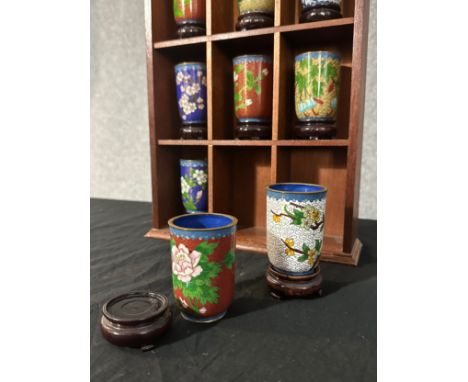 A twelve piece set of Chinese cloisonne enamel floral design tea cups. Each on a wooden stand and presented in a wall mounted