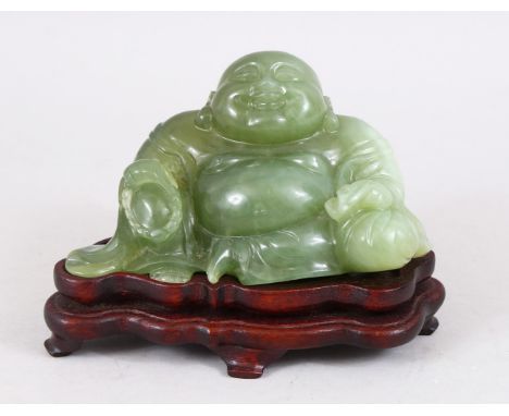 A 19TH / 20TH CENTURY CHINESE CARVED JADE FIGURE OF BUDDHA, in a seated position with a smile on his face, upon a carved and 