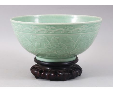 A GOOD CHINESE CELADON CARVED BOWL &amp; HARDWOOD STAND, the bowl carved with formal scrolling lotus and foliage, the inside 