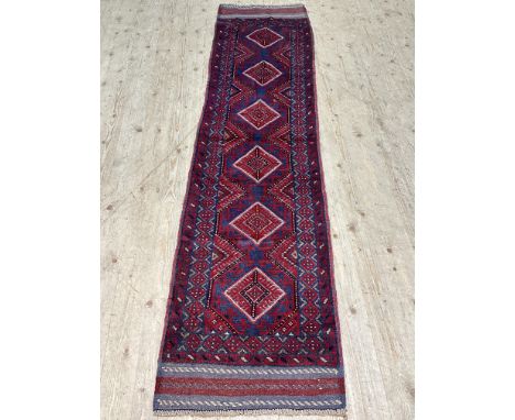A meshwani runner, with a claret ground decorated with blue and red lozenge motifs, 255cm x 62cm 