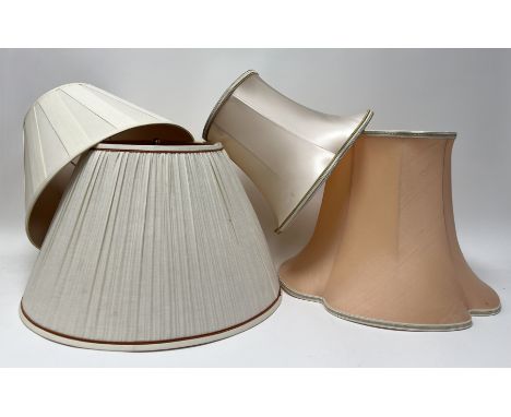 A collection of four lamp shades comprising, a large pleated cream shade with orange piped border to base and top and a brass