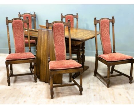 An Ercol oak six piece dining set comprising rectangular dining table with moulded edge, on twin end cup and cover supports (