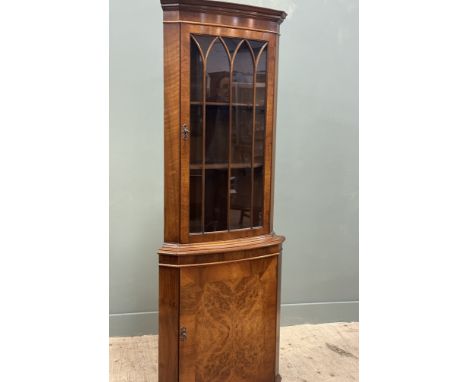 A burr walnut floor standing corner cupboard with glazed door and two shelves with panelled door with shelf interior on brack