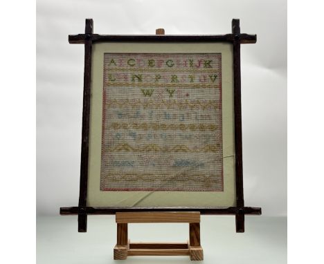 A late 19thc sampler by Jane W. Atkinson with alpaha bet in upper and lower case worked in coloured wools in oak galzed frame