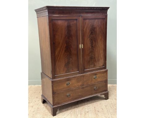A 19th century mahogany linen press, with a moulded dentil cornice above a pair of panelled doors enclosing a hanging rail, t