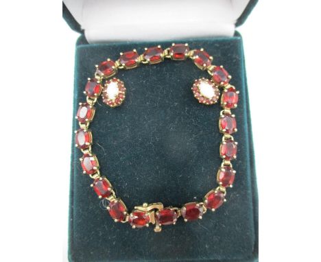 A yellow gold coloured metal bracelet set with garnets, stamped 10ct and two similar earrings, each set with an opal 