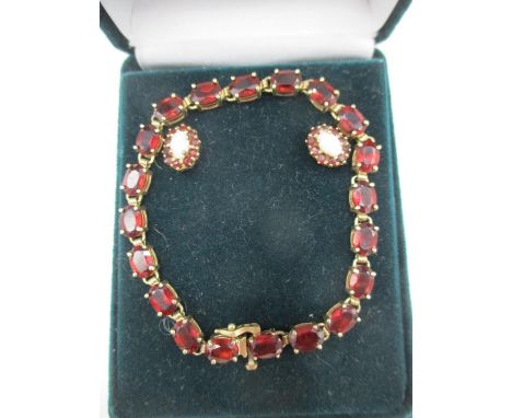 A yellow gold coloured metal bracelet set with garnets, stamped 10ct and two similar earrings, each set with an opal 