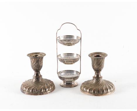 A PAIR OF SILVER CANDLESTICKS AND A SILVER THREE TIER STAND (2)Each candlestick with spiral fluted decoration, raised on a ci