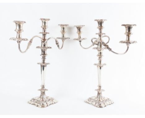 A PAIR OF PLATED THREE LIGHT TABLE CANDELABRAEach with scrolling arms, detachable sconces and raised on a shaped square base,