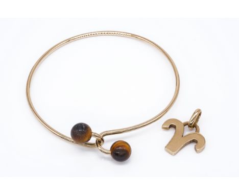 A 9CT GOLD AND TIGER'S EYE BANGLE AND A 9CT GOLD PENDANT (2)The sprung bangle with tiger's eye bead terminals, detailed Gucci