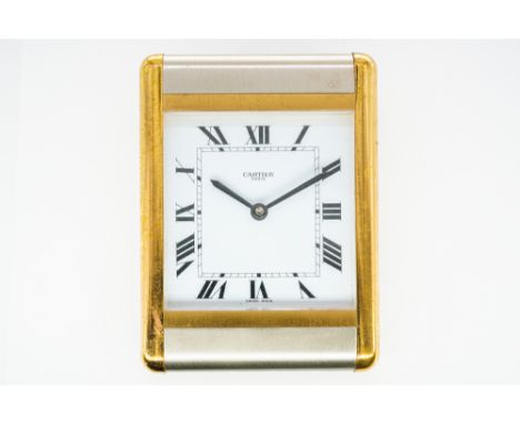 A CARTIER PARIS ALARM CLOCKThe gilt metal rectangular clock with black Roman numerals and black hands to the white enamelled 