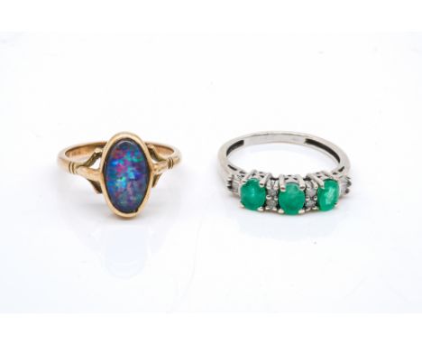 AN EMERALD AND DIAMOND RING AND AN OPAL RING (2)The first ring claw set with three oval cut emeralds and with two pairs of ci