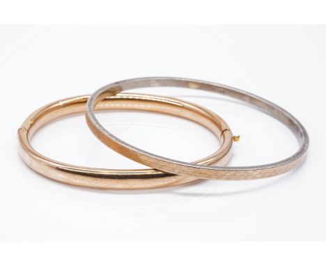 A GOLD HOLLOW OVAL HINGED BANGLE TOGETHER WITH A SILVER AND GOLD FRONTED CIRCULAR BANGLE (2)The hollow gold bangle unmarked, 