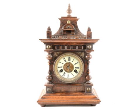 A German stained wood mantel clock, carved case, circular dial with Roman numerals, fourteen-day strike movement on a gong, 4