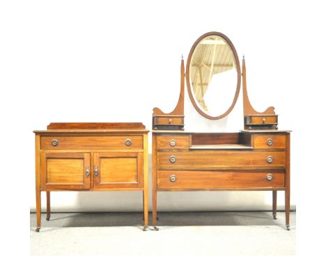 An Edwardian inlaid mahogany dressing table, oval bevelled mirror back, two raised trinket drawers, fitted with two short and