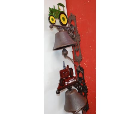 Two reproduction cast metal ranch bells with tractor pediments.