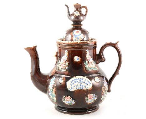 A large bargeware teapot, inscribed 'Present from Jane Dennis to J &amp; R E Petty, 1906', with teapot finial, applied band o