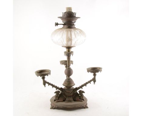 A Victorian plated oil lamp epergne centrepiece, the column supporting the cut-glass reservoir, three branches, issuing on a 