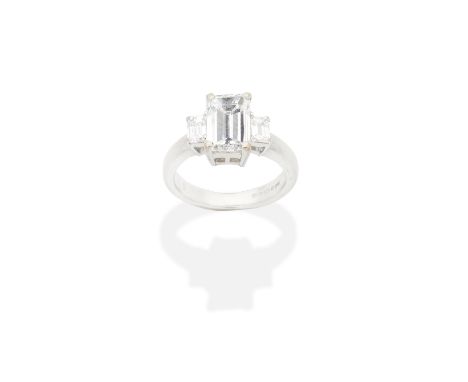 DIAMOND THREE-STONE RINGThe step-cut diamond, between step-cut diamond shoulders, mounted in 18 carat white gold, principal d