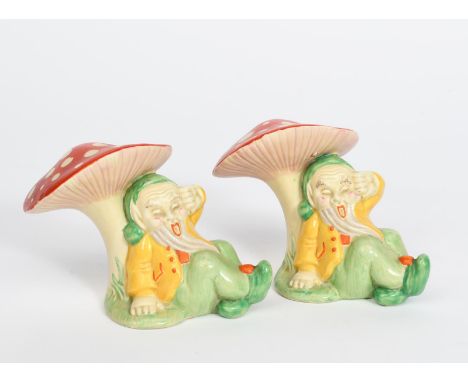 A pair of Clarice Cliff Gnome book ends, each modelled resting underneath a toadstool, painted in colours printed factory mar