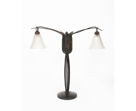 An Art Deco wrought iron two-light lamp in the manner of Edgar Brandt,  the central clustered stem supporting floriform termi
