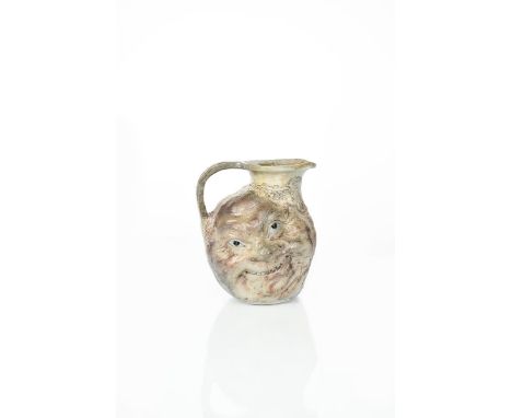 A Martin Brothers stoneware face jug designed by Robert Wallace Martin, modelled with a smiling face to one side, the reverse
