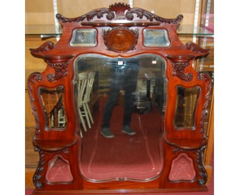 A late Victorian floral carved mahogany bevelled overmantel mirror, inset with seven various shaped mirror plates, with furth