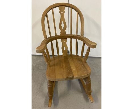 A child's light wood Windsor Rocking chair with turned legs and supports and cut out detail to back. Approx. 70cm tall. 