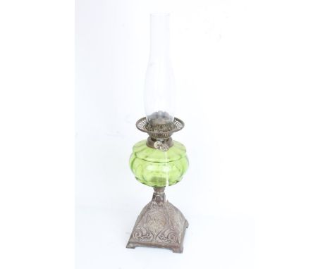 Oil lamp with clear glass chimney, green glass reservoir and scroll cast metal foot, 55cm high
