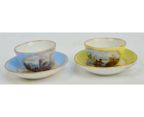 A pair of c.1900 German miniature cups and saucers in blue and yellow, each hand painted with coastal scenes and bearing cros