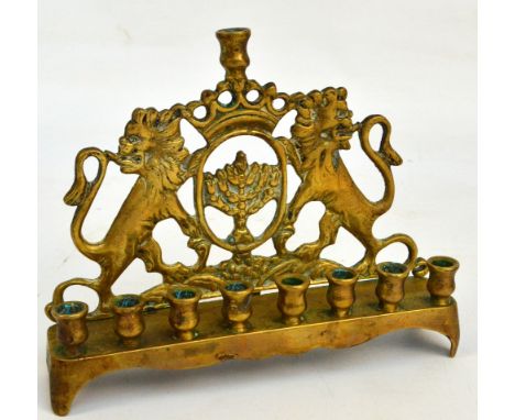 A late 19th/early 20th century brass Hanukkah lamp with cast and pierced back plate depicting a menorah surmounted by crown w