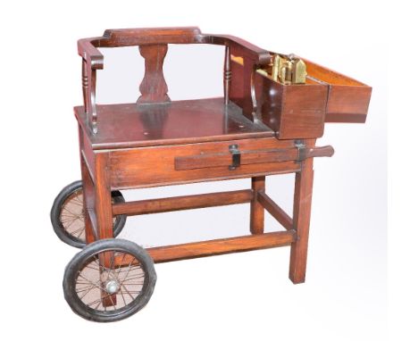 An early 20th century oak framed set of jockey scales, with rounded bar back and spindle support beside a brass arm, square s