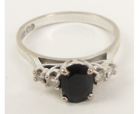 An 18ct white gold dress ring, the central sapphire flanked by two small diamonds, on raised gallery, size O/P.