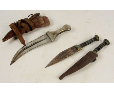 A late 19th/early 20th century Eastern dagger with leather scabbard, and two further daggers, on with scabbard, one lacking s