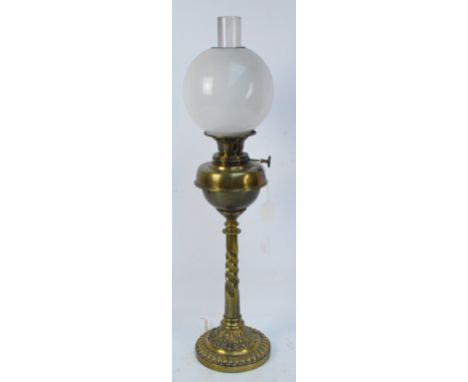 A late Victorian brass oil lamp converted to electricity with opaque globular shade, wrythen moulded stem and gadrooned foot,