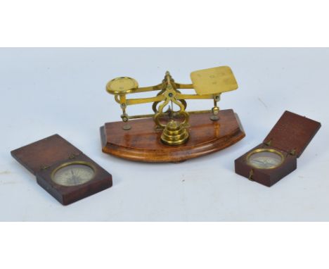 Two George III wooden cased pocket compasses with paper dials and a small set of balance scales on bowfront plinth (3).