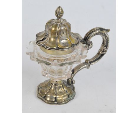 An early 19th century Continental (probably German) ornate glass mustard pot with plated mounts, cover, handle, in organic sh