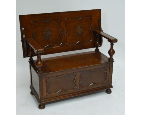 An early 20th century oak monk's bench with panelled sliding lid, hinged seat, and squat bun feet, width 107cm.