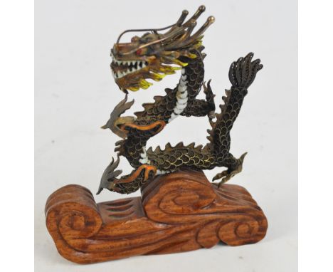 An early 20th century Chinese silver gilt and enamel filigree work figure of a dragon with inset eyes, on foliate decorated h