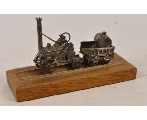 An Elizabeth II hallmarked silver novelty model of Stephenson's Rocket, with barrel to the cart, mounted on a wooden block wi